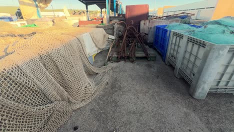sauntering among the fishing gear housed in the fishing village's warehouse, observing aged metal anchors and crates brimming with fishing nets