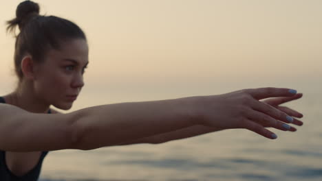Focused-girl-reaching-hands-forward-practicing-yoga-asana-on-seacoast.