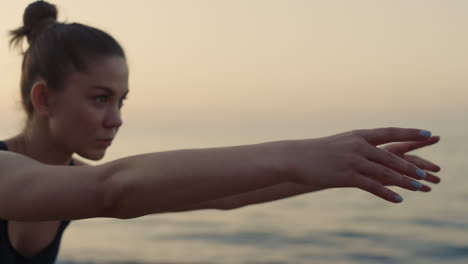 focused girl reaching hands forward practicing yoga asana on seacoast.