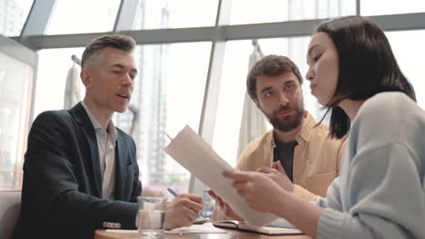 a work team discusses details of some data in a report in a coffee shop 2