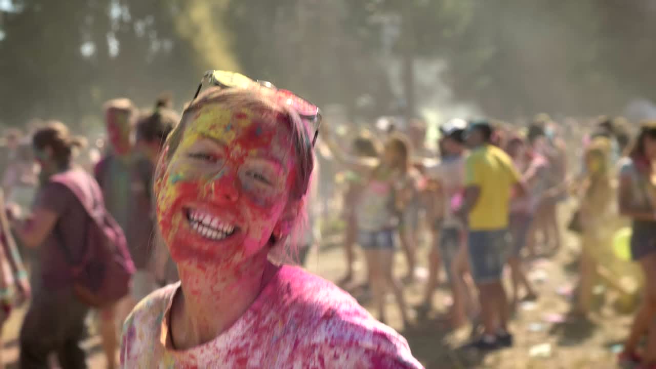 Young lively girl in colourful powder is jumping and dancing on holi festival in daytime in summer, color concept, emotional concept