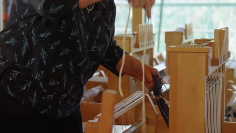 Mid-section-of-old-caucasian-senior-woman-working-on-handloom-machine-in-a-workshop-4k