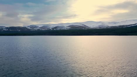 Forwards-fly-above-lake-in-winter-mountain-landscape