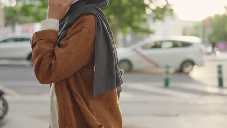 woman in hijab talking on smartphone on city street