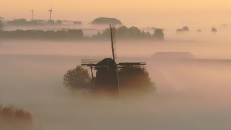 Vista-Aérea-Del-Antiguo-Molino-De-Viento-Tradicional-En-Un-Prado-Con-Niebla-Baja-Al-Amanecer,-Frisia,-Países-Bajos