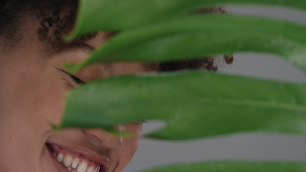retrato de cerca hermosa mujer de raza mixta con piel suave y natural que se esconde detrás de las plantas asomándose juguetona atractiva mujer que disfruta de un concepto de belleza saludable para el cuidado de la piel