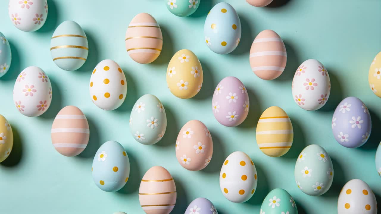 Pulling back camera revealing decorated pastel eggs on mint tabletop, showing diagonal rows