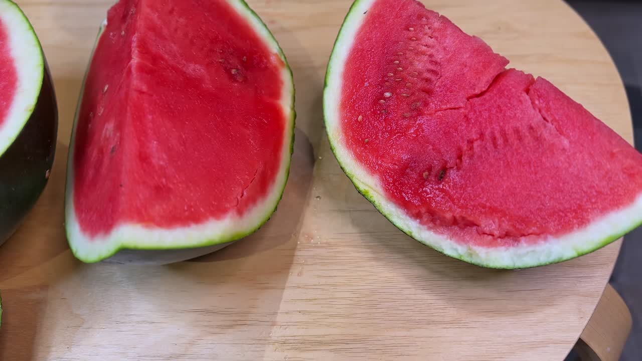Close-up of hands holding a juicy watermelon half with visible seeds and carved slices, perfect for food, health, nutrition, summer refreshment, and lifestyle projects