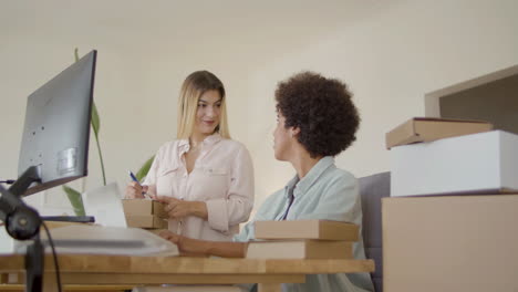 dos trabajadoras de tiendas en línea hablando en la oficina