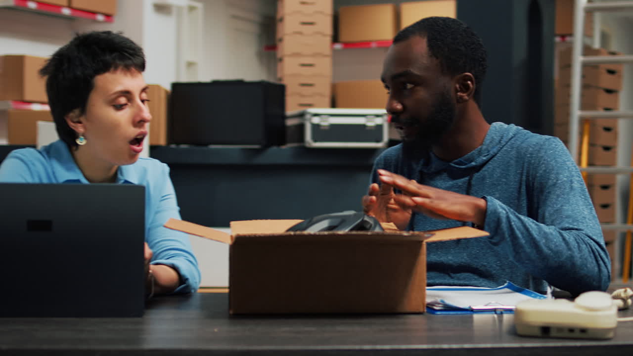 Two people talking at desk with box