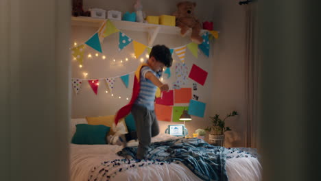 niño feliz saltando en la cama vestido con disfraz jugando a un juego disfrutando de la imaginación lúdica en un dormitorio colorido en casa