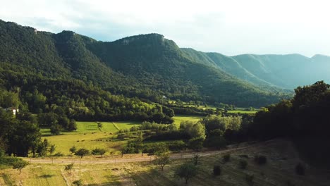 Impressive-aerial-views-of-green-forests-between-mountains,-with-a-beautiful-lake-adding-serenity-to-the-tranquil-beauty-of-the-landscape