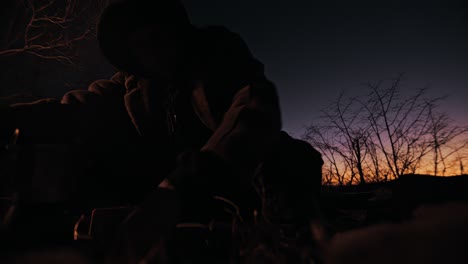 Campfire-Coffee:-Young-homeless-man-holding-hands-over-his-campfire-to-keep-the-wind-from-blowing-it-out