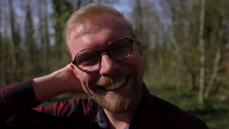 happy handsome young man smiles, dolly in outside in nature, sunny day