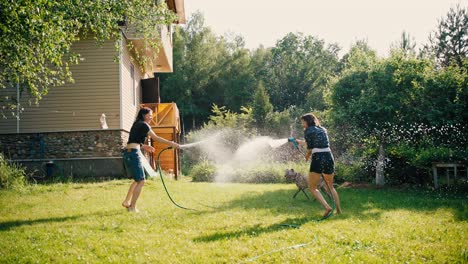 two young women are having fun splashing each other with water from hoses