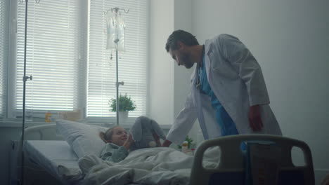 doctor checking on little patient in hospital ward. sick girl hugging plush toy