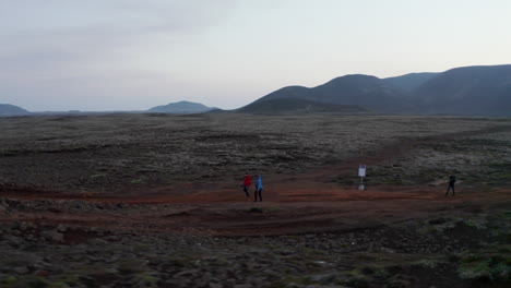 Drone-orbit-point-of-view-group-of-tourist-hiker-walking-pathway-in-isolated-rocky-desert-in-Iceland.-Birds-eye-traveler-trekking-exploring-icelandic-trail