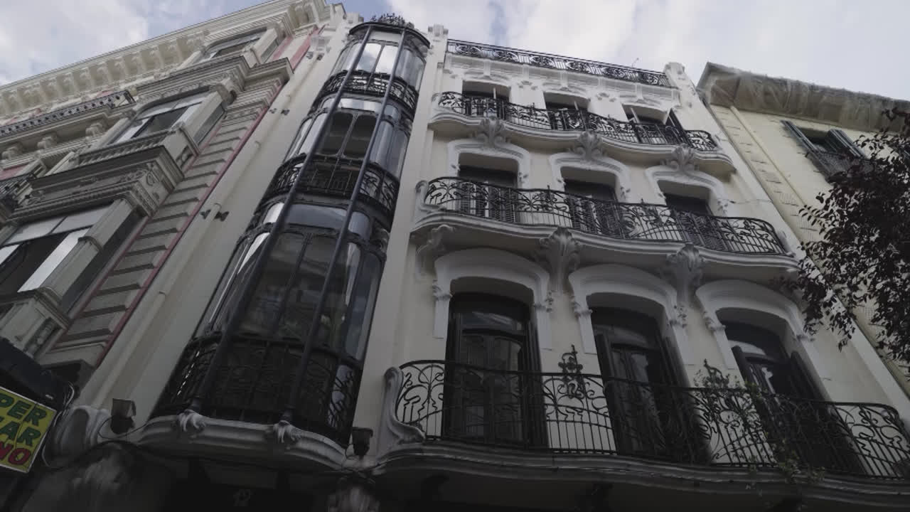 Beautiful slow motion zoom in shot of a classic building in the center of Madrid with trees around it on De Goya street in Madrid, Spain.