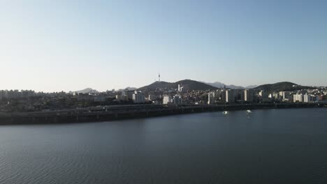 toma aérea volando sobre el río han con la ciudad de seúl y la torre en el fondo, corea del sur