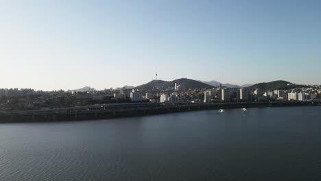 aerial shot flying over han river with seoul city and tower in background, south korea