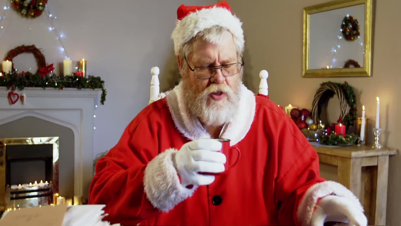 산타클로스가 의자에서 휴식을 취하고 커피를 마시고 있습니다.