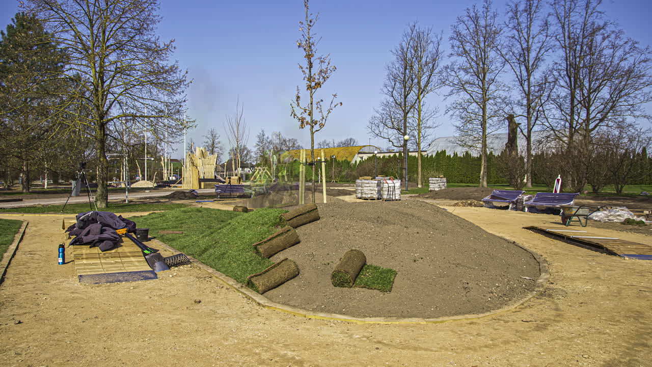 Gärtner verlegen Rasen, indem sie Rollrasenbahnen in einer Gartenparkanlage eines Wohngebiets ausrollen.