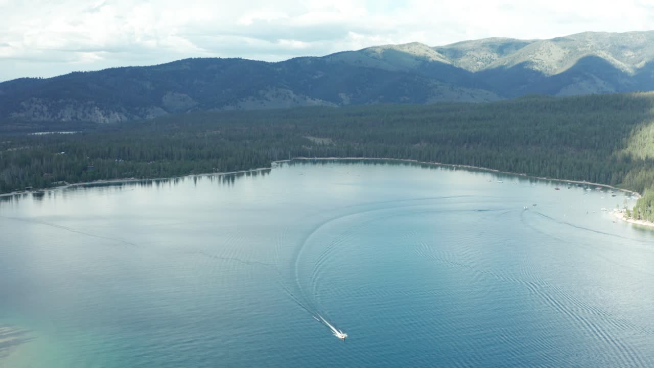 드론 추적 영상으로 파란 물로 둘러싸인 레드피시 호수에서 보트를 타고 있습니다.