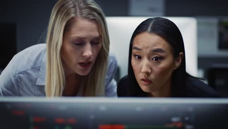 two focused professionals analyzing data on a computer screen in a modern office environment, displaying intense concentration and teamwork during a critical moment