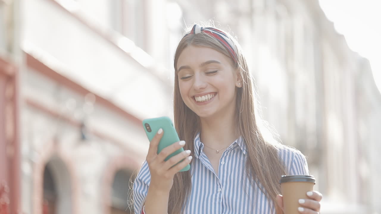 Giovane donna felice che invia un messaggio vocale su smartphone all'aperto