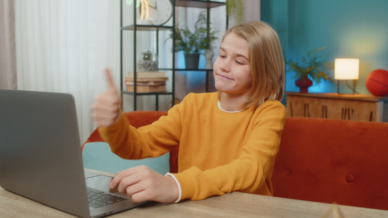 Teenager boy conducting video conference on laptop waving hand and greeting friend on couch at home