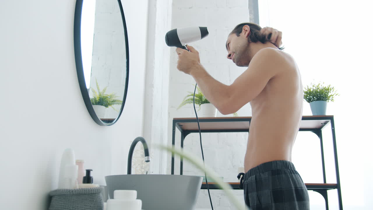 남자 가 화장실 에서 머리 를 건조 시키고 있다