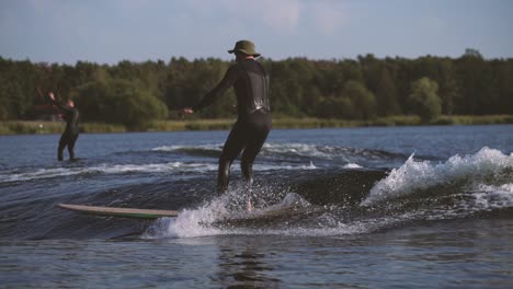 surfer surfing longboard in wave touches wave with cross step and nose ride behind a boat in slow motion