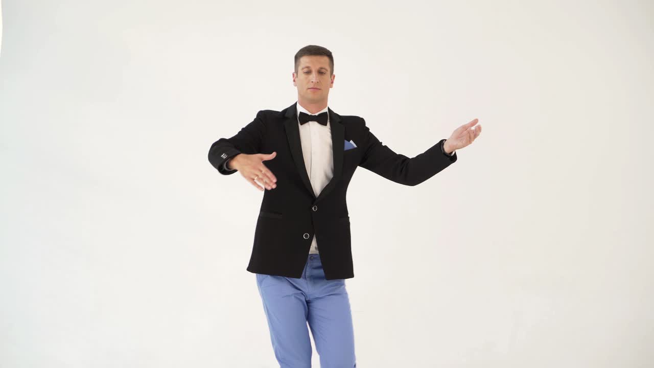 funny man in suit is depicting a man dancing a waltz with a partner at concert on a white background in the studio