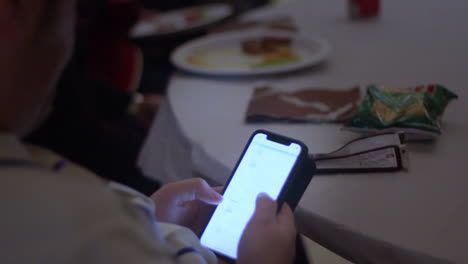 primer plano de una persona masculina escribiendo y deslizando el dedo en el teléfono inteligente después de cenar en el restaurante