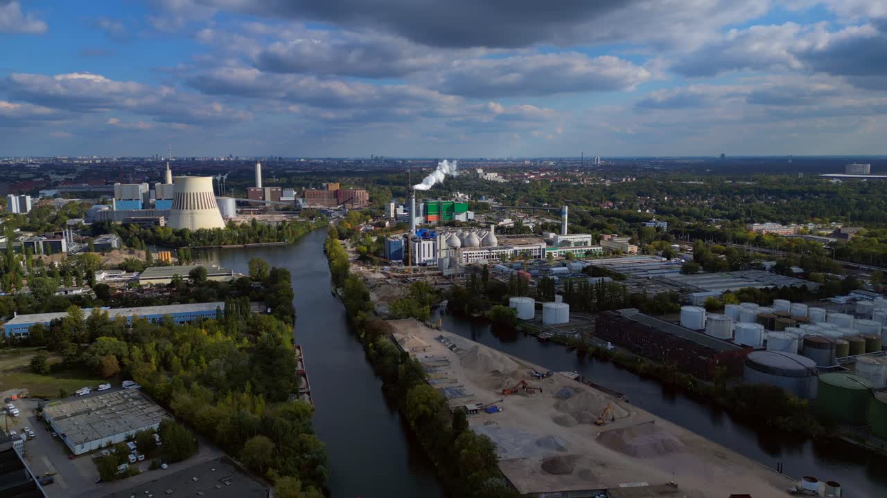 Industrial landscape with factories, a large power plant, and storage tanks bordering river in berlin germany. Perfect aerial view flight static tripod hovering drone