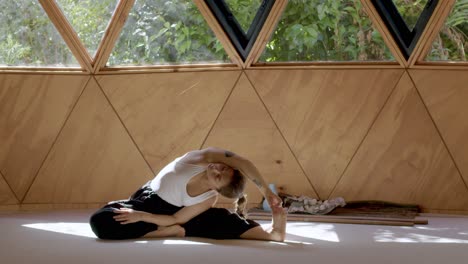 Peaceful yoga practice with a Latina woman in a geometric outdoor studio, focusing on mindfulness and relaxation, stretching side of body and hand to toes