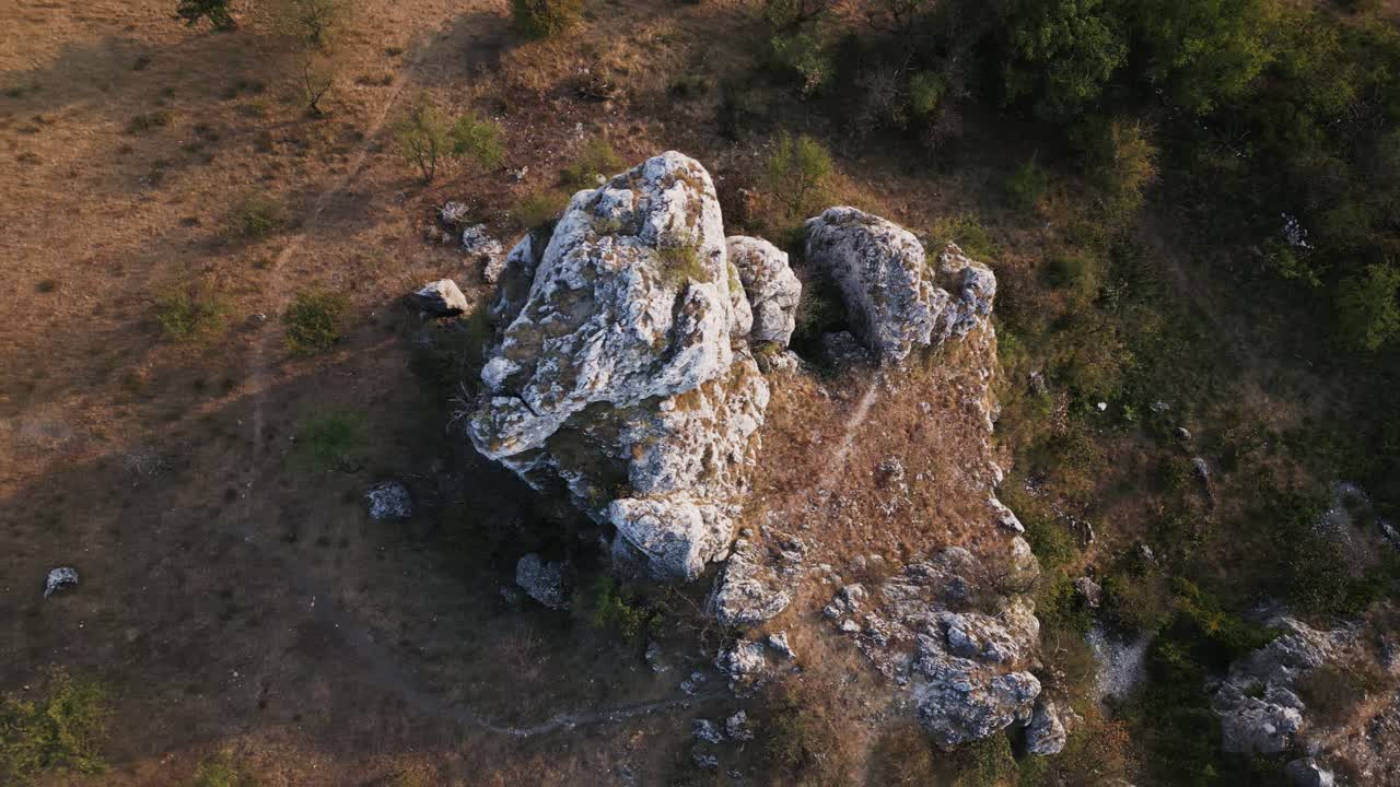 Aerial view of a large rugged limestone rock formation surrounded by sparse vegetation and dry terrain.