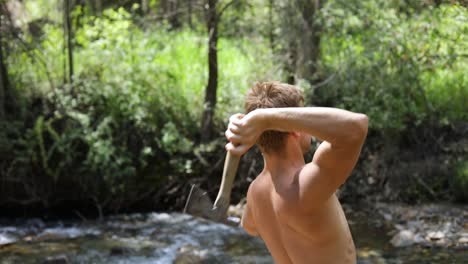 slow motion shot of a shirtless man practicing his axe throwing skill by trying to throw his hatchet at a pine tree-4