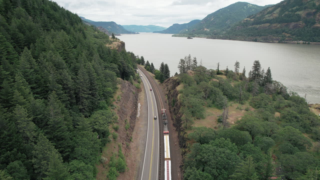 carretilla aérea hacia adelante siguiendo el tren de carga, el tráfico de la carretera a lo largo del río columbia