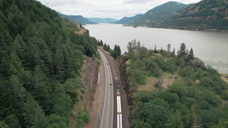 aerial dolly forward following freight train, highway traffic along columbia river