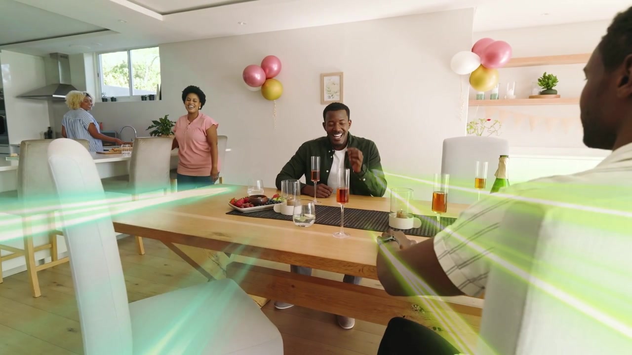 Man sitting taking call, laughing after light rays sweeping over table, group relaxing for social