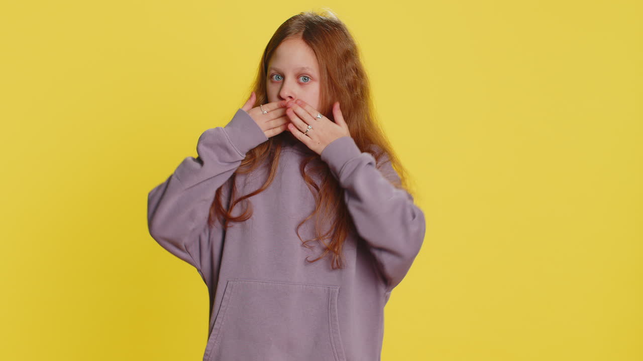 Bambina spaventata che chiude la bocca con le mani rifiutandosi di dire un terribile segreto incredibile verità