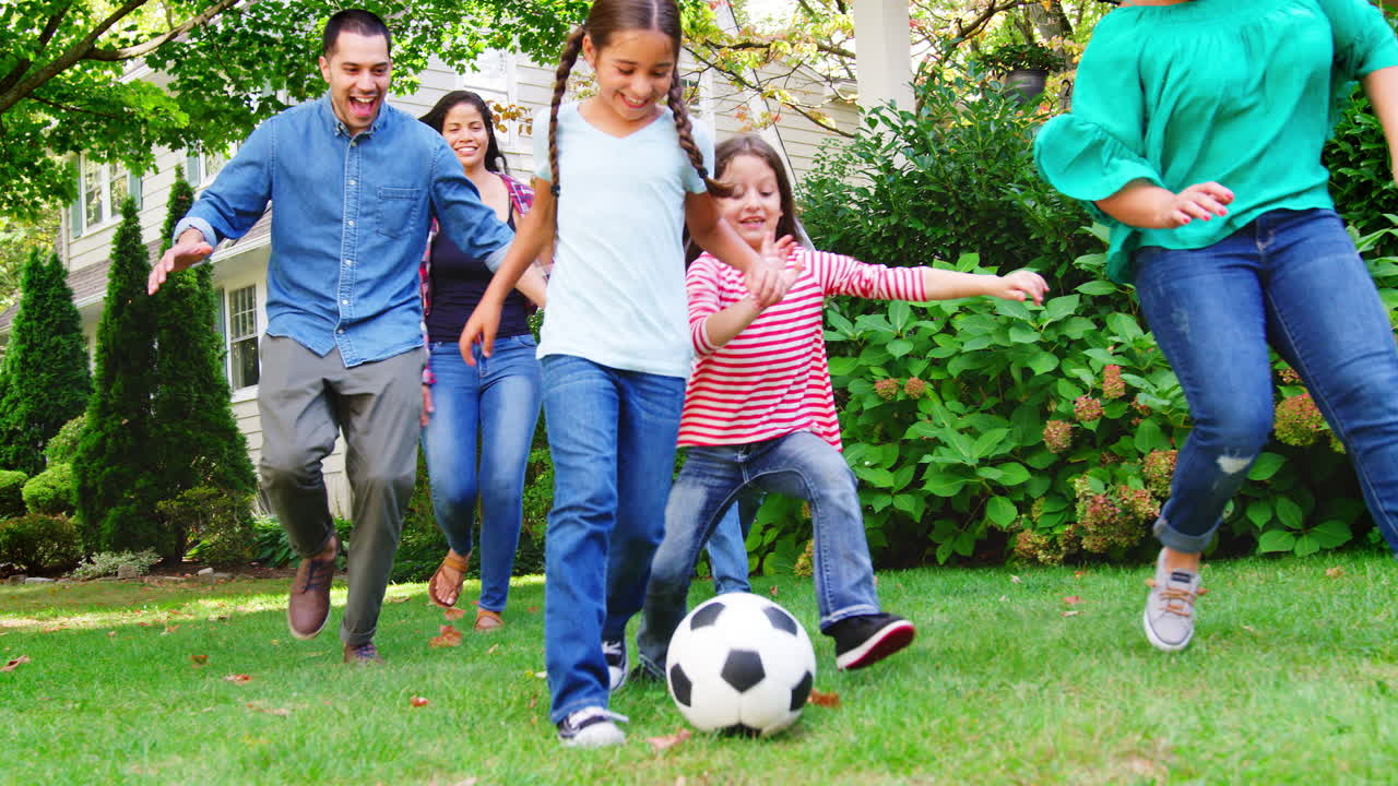 familia de varias generaciones jugando al fútbol en el jardín