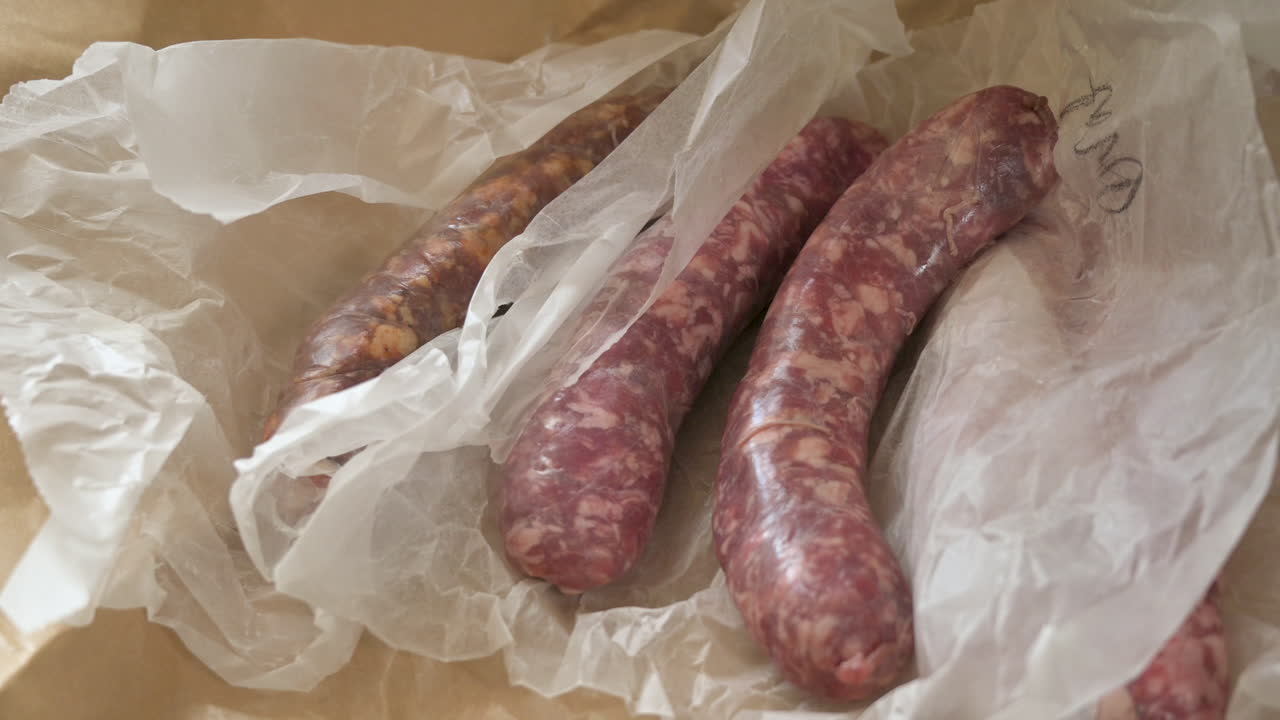 deliciosa salchicha de cerdo cruda en papel de carnicero blanco, zoom en tiro