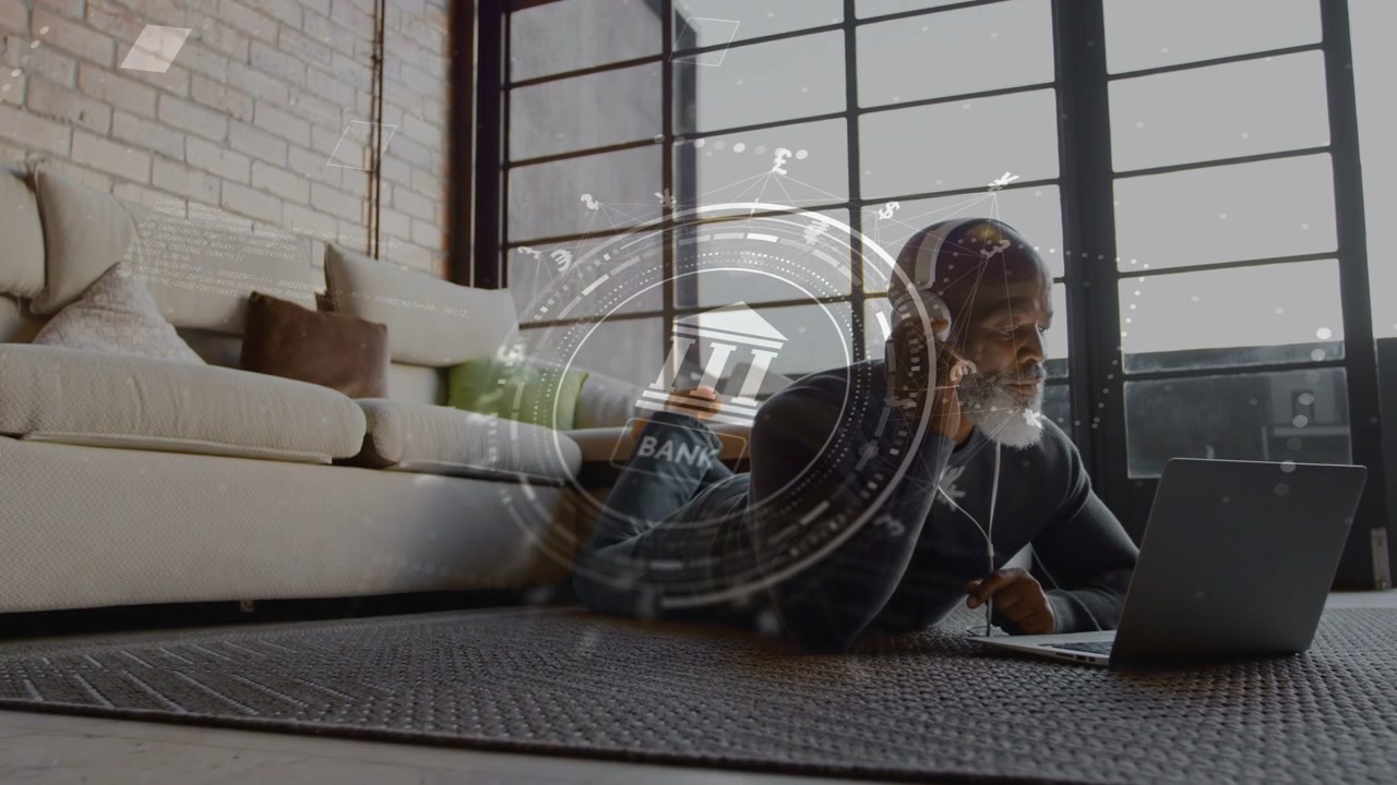 Mature man lying on rug adjusting headphones after laptop audio alert while viewing banking HUD