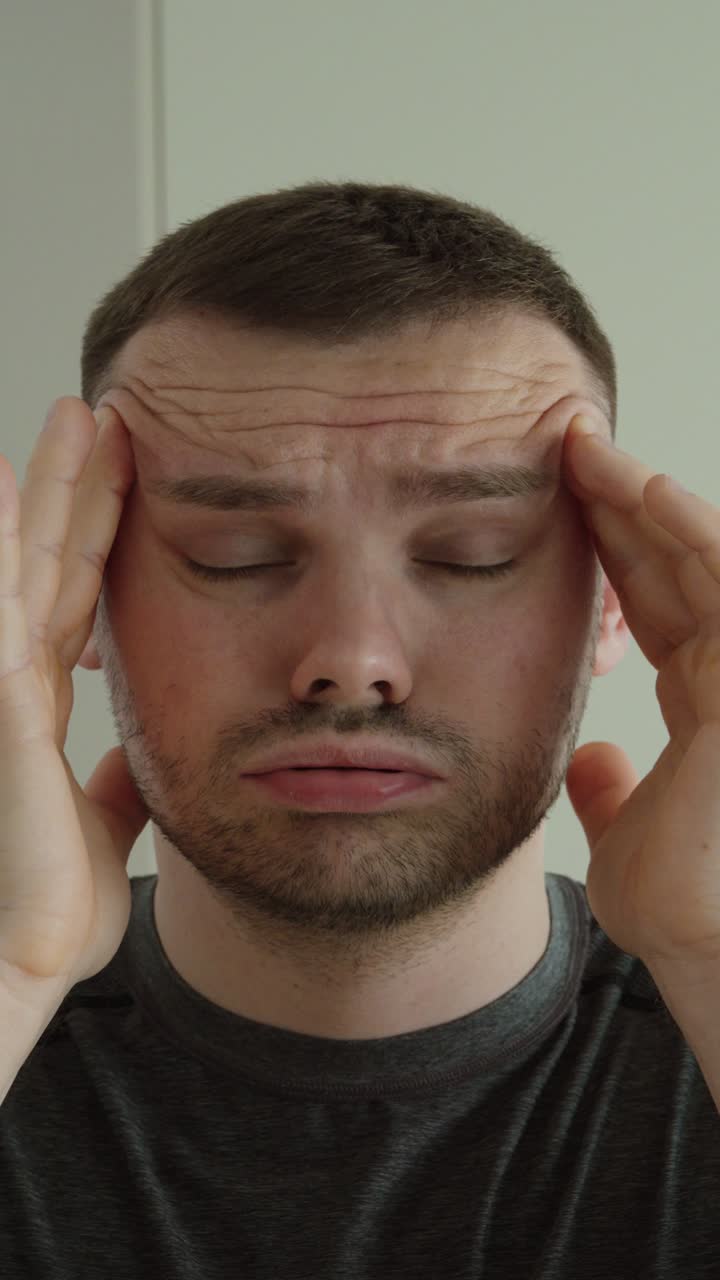 Primo piano di un uomo che si massaggia le tempie, a rappresentare stress, affaticamento e benessere mentale.