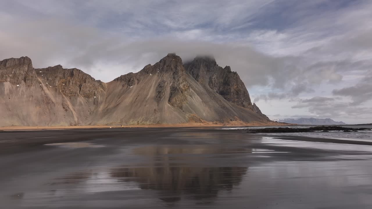Vestrahorn and Eystrahorn peaks at Stokksnes, Iceland aerial view, ocean waves and rugged mountain silhouettes.