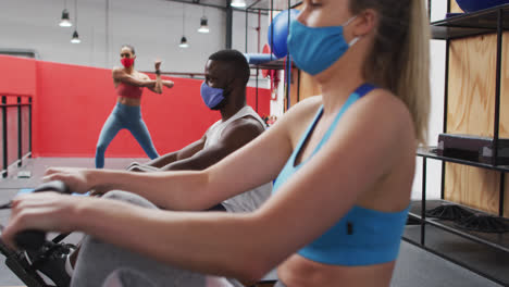 grupo diverso con máscaras faciales haciendo ejercicio en el gimnasio