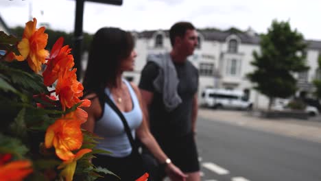 couple walking past flowers and cars