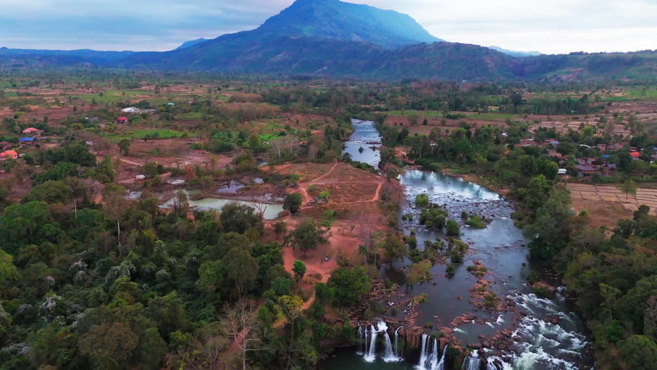 Aerial orbit of winding river and lush green valleys in Bolaven plateau , Laos